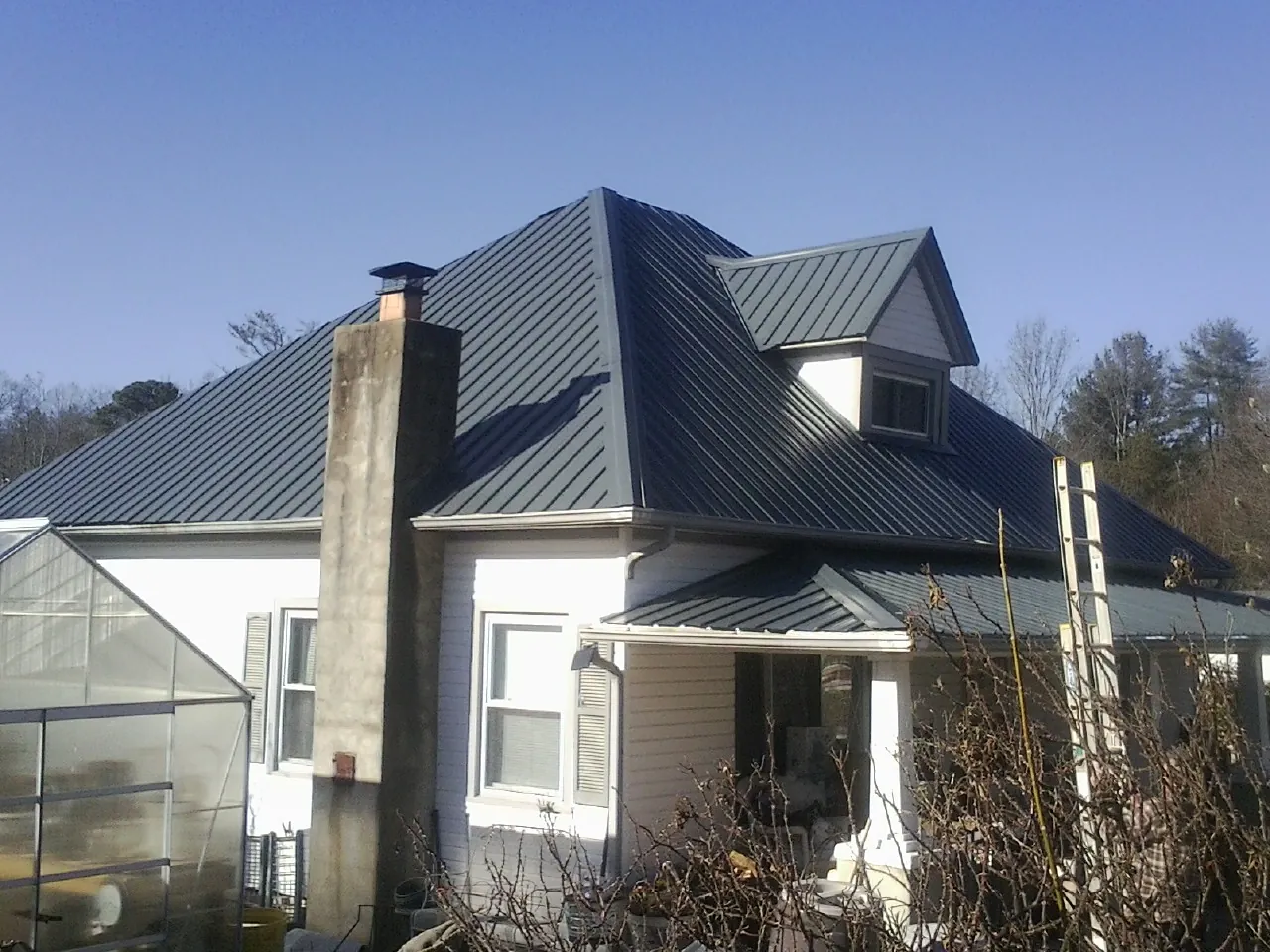 Dark blue standing seam metal roof on a white farmhouse with dormer — Slate & Tile Roof Repair by Roofing Brothers in Wakarusa