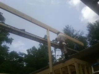 Carpenter setting a ridge beam over a new addition frame — Ice Dam Removal by Roofing Brothers in Wakarusa